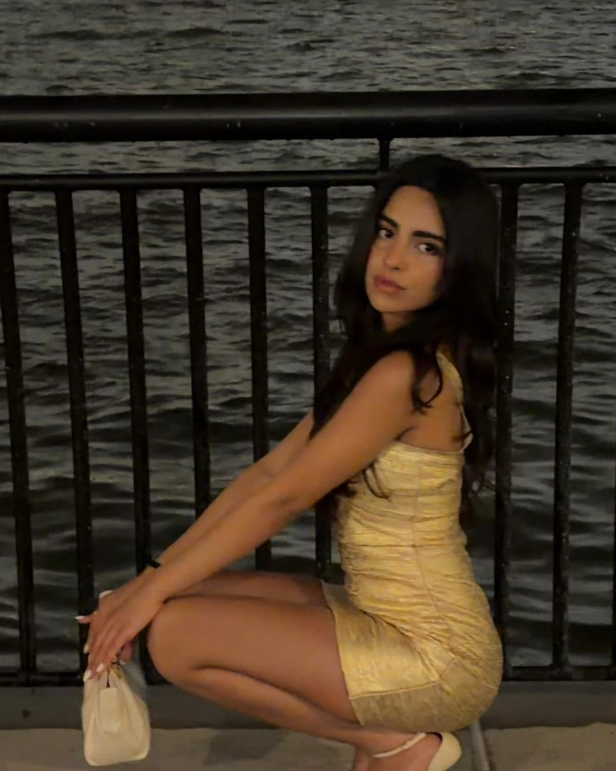 Siya Bhasin in the Naomi gold bandage dress by Casual Threat by the water at night, a New Year's Eve dress